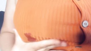 A fat woman in an orange blouse. Lactation through clothes and display of large milk boobs