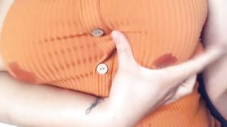 A fat woman in an orange blouse. Lactation through clothes and display of large milk boobs