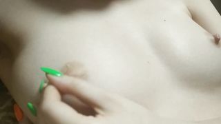 A naughty young girl's finger with a bright manicure play with her nipples